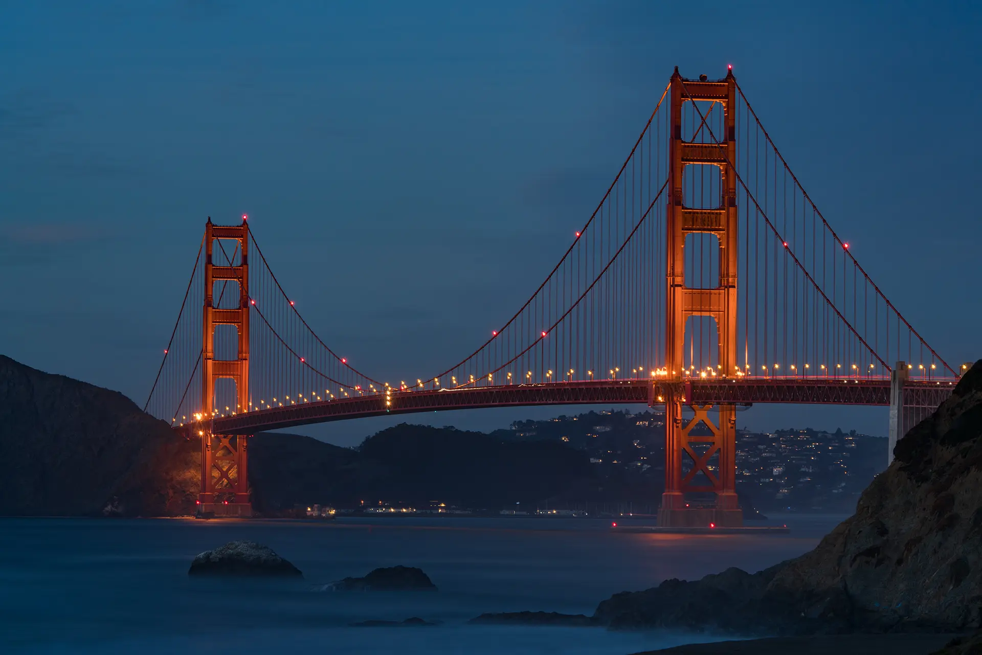 a red suspension bridge lit up with lights at night
