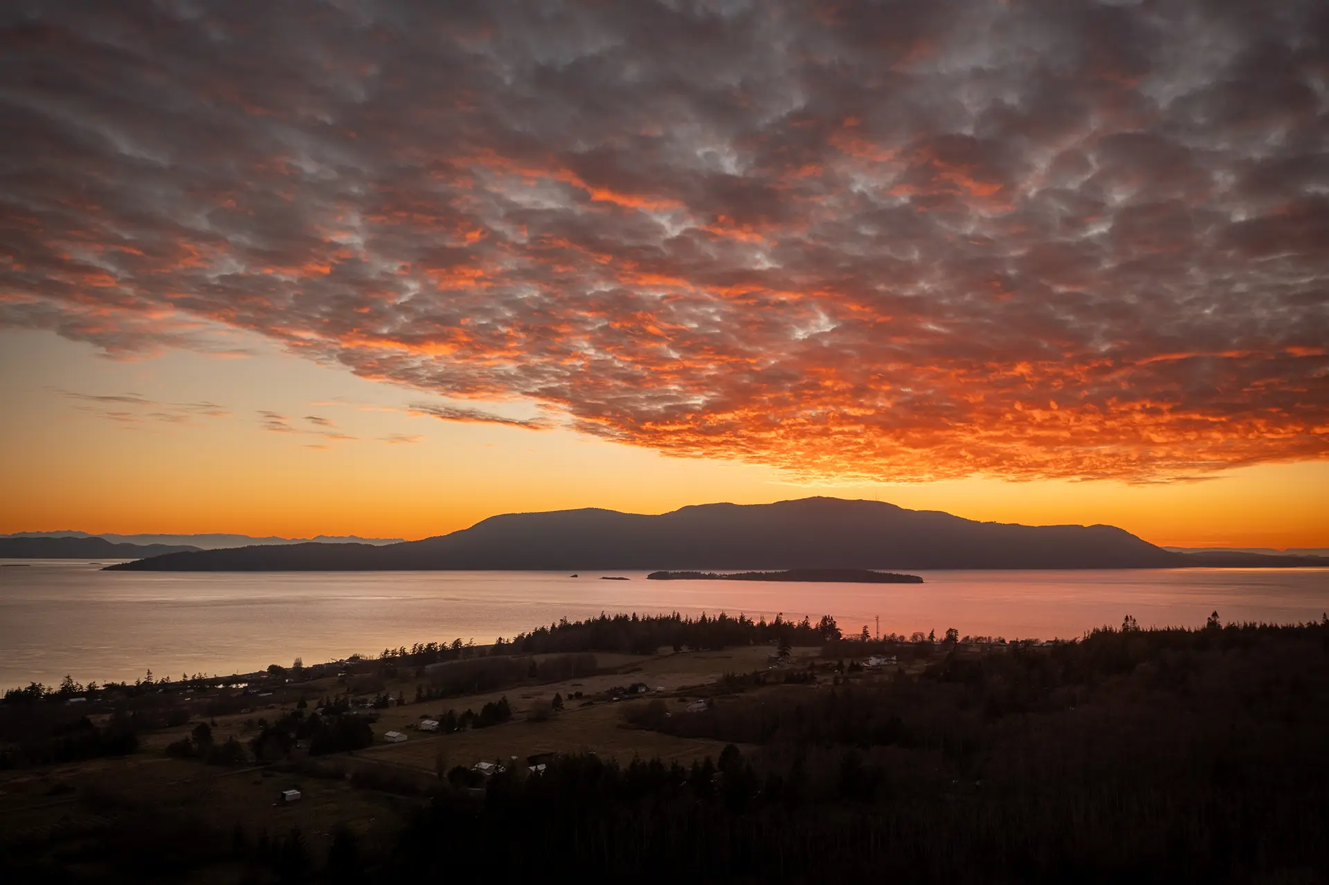 a beautiful sunset over a landmass in the ocean